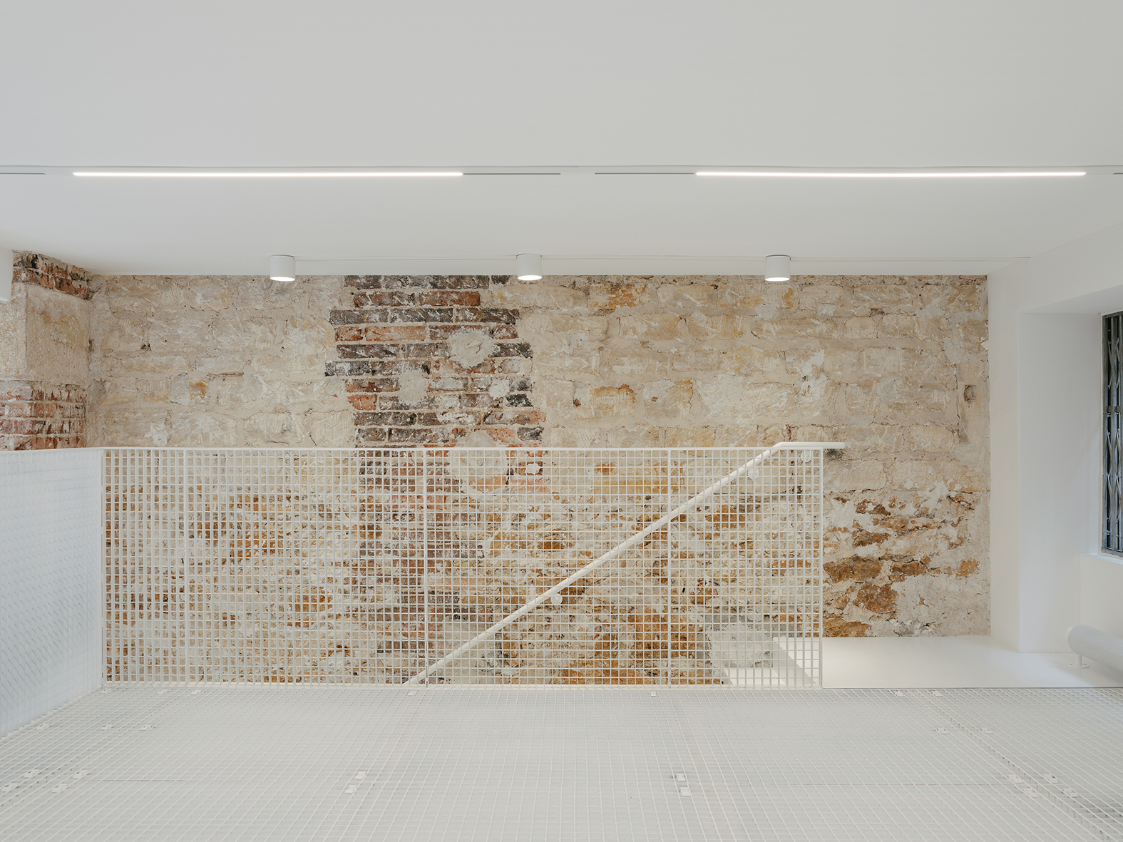 Mur en pierre et brique apparentes, garde-corps en résille métallique